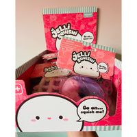 A display box filled with Jellii Squishies, including a pink and purple donut-shaped squishy toy, packaged in pink and white packaging with cartoon graphics.